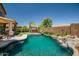 Private backyard featuring a pool with rock waterfall, desert landscaping, putting green, and hot tub at 11936 W Alvarado Rd, Avondale, AZ 85392