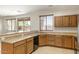 Bright kitchen with wood cabinets, breakfast bar, and stainless steel sink with large window at 12089 N 145Th Dr, Surprise, AZ 85379