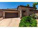 Single-story home featuring a two-car garage, desert landscaping, and mature trees for added privacy and curb appeal at 14314 W Lexington Ave, Goodyear, AZ 85395