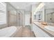 Bright bathroom featuring a soaking tub, glass enclosed shower, and a double sink vanity at 16961 W Holly St, Goodyear, AZ 85395