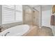 Bright bathroom featuring a large soaking tub and a glass enclosed shower with bench seating at 16961 W Holly St, Goodyear, AZ 85395