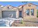 Charming brick and stucco home featuring a gray garage door, desert landscaping, and tile roof at 16961 W Holly St, Goodyear, AZ 85395