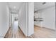 Hallway with wood-look flooring leads to a kitchen with white cabinets and granite countertops at 18153 W Hiddenview Dr, Goodyear, AZ 85338