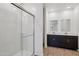 Modern bathroom featuring a glass-enclosed shower and double vanity with dark wood cabinets and wood look tile at 18248 W La Senda Dr, Surprise, AZ 85387