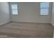 Bedroom featuring plush carpeting and bright natural light from two windows at 18248 W La Senda Dr, Surprise, AZ 85387
