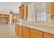 Bright kitchen with granite countertops, wooden cabinets, tile backsplash, and view of the living room fireplace at 2652 N 143Rd Dr, Goodyear, AZ 85395