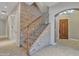 Staircase with stone accent wall, carpeted steps, metal railing, and wood banister at 2652 N 143Rd Dr, Goodyear, AZ 85395