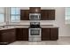 Modern kitchen with stainless steel oven and microwave, as well as dark wood cabinetry and countertop space at 4745 W Fremont Rd, Laveen, AZ 85339