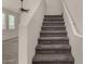 Carpeted staircase with white walls and railing, next to living area with ceiling fan at 4745 W Fremont Rd, Laveen, AZ 85339