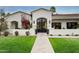 Up close front exterior showcasing desert landscaping, grass lawn and an arched entry with glass doors at 8045 E Del Caverna Dr, Scottsdale, AZ 85258