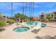 Community pool with a hot tub and plenty of seating under tall palm trees and clear blue skies at 8651 E Royal Palm Rd # 121, Scottsdale, AZ 85258