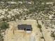 Aerial view of a desert property featuring a charming single-story home with an attached two car garage and a long driveway at 10772 N Biznaga St, Florence, AZ 85132
