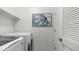 Well-lit laundry room with white washer and dryer, upper shelf, and modern artwork at 14870 W Encanto Blvd # 1059, Goodyear, AZ 85395