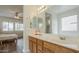 Bathroom featuring wood cabinets, a large mirror, modern lighting, and ensuite bedroom access at 16526 W Calle Lejos --, Surprise, AZ 85387