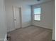 Clean bedroom featuring neutral carpeting, a window with blinds, and a classic white door at 18265 W La Senda Dr, Surprise, AZ 85387