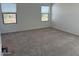 Bedroom featuring neutral carpet, two windows with blinds, and white walls at 18265 W La Senda Dr, Surprise, AZ 85387
