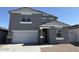 Two-story home with a gray exterior, paved driveway, attached two-car garage, and desert landscaping at 18265 W La Senda Dr, Surprise, AZ 85387