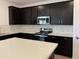 Modern kitchen with stainless steel appliances, stone countertops, and dark wood cabinets at 18265 W La Senda Dr, Surprise, AZ 85387