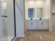 Modern bathroom featuring dual sinks, tile floors, and a glass-enclosed shower at 18271 W La Senda Dr, Surprise, AZ 85387