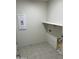 Clean and functional laundry room with tile flooring and a built-in shelf at 18717 N 267Th Dr, Buckeye, AZ 85396