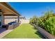 Green backyard with artificial turf, a covered patio, and lush landscaping at 20641 W College Dr, Buckeye, AZ 85396