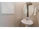 Elegant powder room featuring pedestal sink, decorative mirror, and stylish wall art at 20641 W College Dr, Buckeye, AZ 85396
