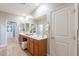 Bright bathroom with double sinks, wood cabinets, and a door to a walk-in closet at 20641 W College Dr, Buckeye, AZ 85396