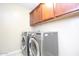 Functional laundry room with front loading washer and dryer, and upper cabinets at 2213 W Marconi Ave, Phoenix, AZ 85023