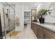 Bathroom featuring wood cabinets, double sinks, a glass shower, and a hallway leading to the bedroom at 26943 N 74Th Ave, Peoria, AZ 85383