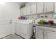 Bright laundry room with white cabinetry, storage space, and modern washer and dryer at 26943 N 74Th Ave, Peoria, AZ 85383
