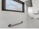 Shower space with white tile surround, shower head, grab bar and frosted window at 3208 W Port Royale Ln, Phoenix, AZ 85053