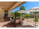 Outdoor patio with a table, chairs, and sun umbrellas, backing to landscaped grounds at 35990 N Desert Tea Dr, Queen Creek, AZ 85140