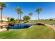 Beautiful community pond featuring palm trees, bridge, lush grass, and scenic views under a bright blue sky at 35990 N Desert Tea Dr, Queen Creek, AZ 85140