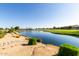 Serene pond view with lush landscaping, clear blue water, and scenic golf course views in a residential community at 35990 N Desert Tea Dr, Queen Creek, AZ 85140