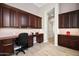Well-lit home office features custom built-in cabinets, desk, and neutral paint with tile flooring at 41809 N La Crosse Trl, Anthem, AZ 85086