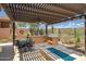 A built in grill and a fire pit beneath a pergola in a desert landscape at 41809 N La Crosse Trl, Anthem, AZ 85086