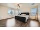 Spacious main bedroom with dark wood floors, a tufted headboard, and bright natural light at 45311 W Woody Rd, Maricopa, AZ 85139