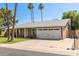 Single-story home with a well-maintained lawn, palm trees, and a two-car garage under a blue sky at 5127 E Tamblo Dr, Phoenix, AZ 85044