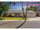 Charming single-story home featuring lush green lawn, palm trees, and desert landscaping at 5127 E Tamblo Dr, Phoenix, AZ 85044