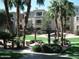 Exterior view of an apartment building with palm trees, lush landscaping, and a shaded pergola with a picnic table at 5345 E Van Buren St # 115, Phoenix, AZ 85008