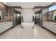 A modern bathroom with dual vanities, freestanding tub, stylish mirrors, and and walk-in showers at 9148 N 66Th Pl, Paradise Valley, AZ 85253