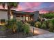 Landscaped front yard with flowers leading to the front of the contemporary home at dusk at 9148 N 66Th Pl, Paradise Valley, AZ 85253