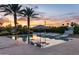 Resort-style pool with in-water loungers and sunbeds, set amidst lush landscaping and swaying palm trees at sunset at 9148 N 66Th Pl, Paradise Valley, AZ 85253