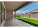 Covered back patio overlooks a lush artificial lawn and block fence at 9738 E Tumeric Ave, Mesa, AZ 85212