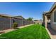 Fully fenced backyard showcasing low maintenance artificial grass and desert landscaping at 9738 E Tumeric Ave, Mesa, AZ 85212