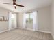 Bright bedroom features two windows with white curtains, carpet floors, and a ceiling fan at 9738 E Tumeric Ave, Mesa, AZ 85212