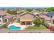 Aerial view of a home with a backyard featuring a uniquely shaped pool, green lawn, covered patio, and mature landscaping at 981 N Quail Ln, Gilbert, AZ 85233