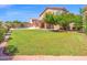 Backyard with covered patio, green grass, and mature landscaping provides a beautiful outdoor living space at 981 N Quail Ln, Gilbert, AZ 85233