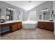 Well-lit bathroom featuring double sinks, a soaking tub with unique windows and vanities at 981 N Quail Ln, Gilbert, AZ 85233