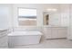 Bright bathroom featuring a soaking tub, white cabinets, and a large window at 10013 S 36Th Ave, Laveen, AZ 85339